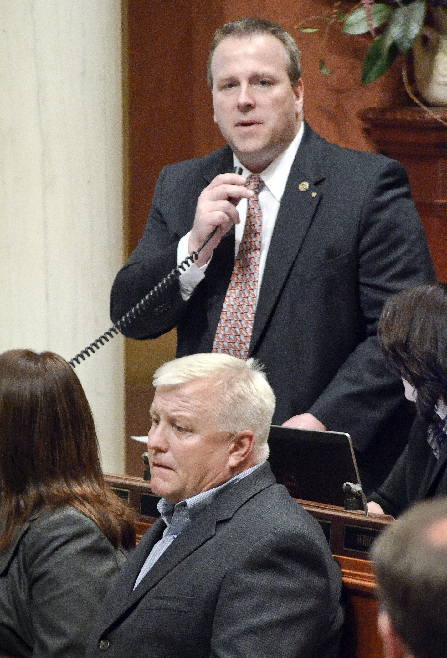 Rep. Bob Barrett speaks on the House floor March 31 in support of a bill he sponsors that would designate the Nicholas Patrick Spehar Memorial Highway. In front of Barrett, and representing the Spehar family, sits Andy Wilkerson, who originally brought the idea to the legislator. Photo by Andrew VonBank